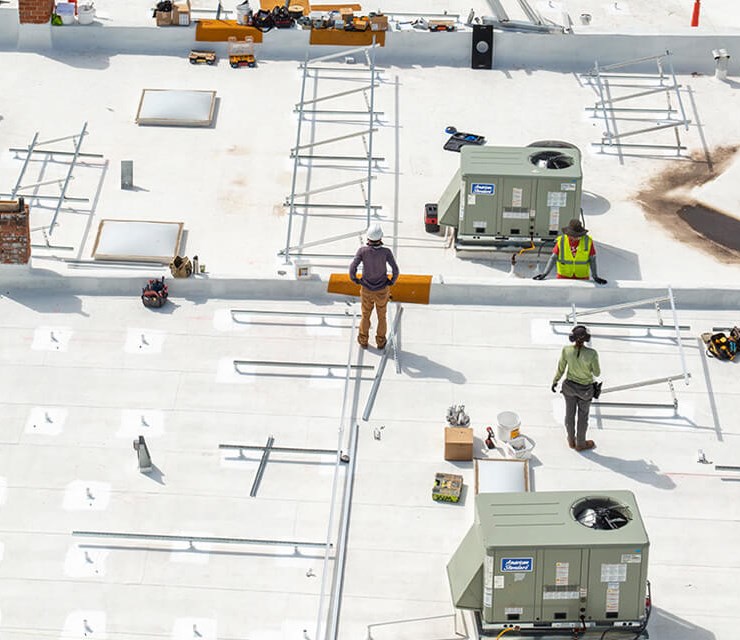 Commercial flat roof with roofing contractors on top working